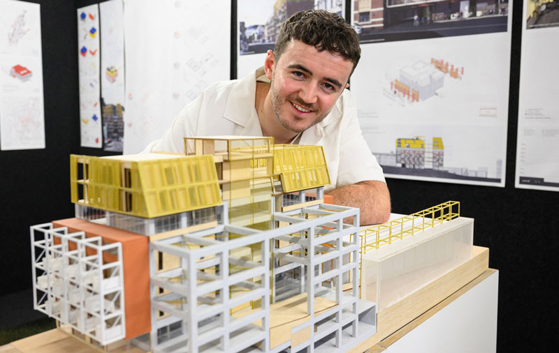 Architecture student presenting a detailed timber and steel building model